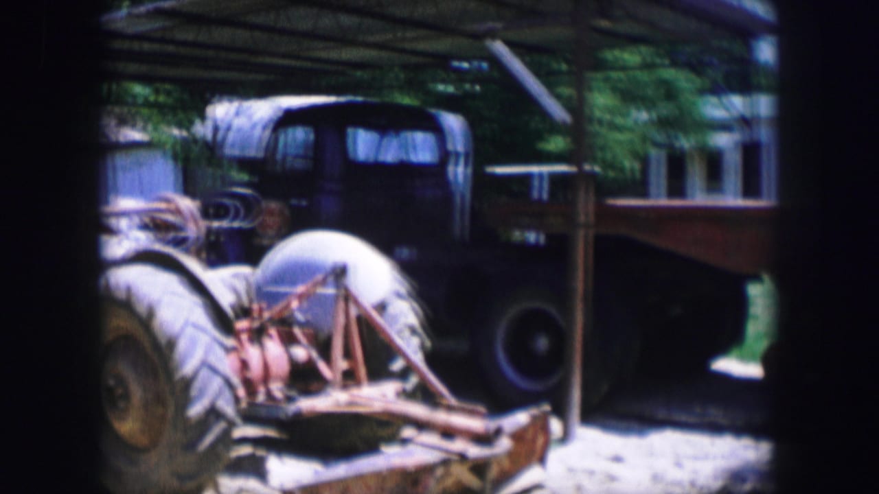Tractor and flatbed trailer seen through dark film-frame borders.