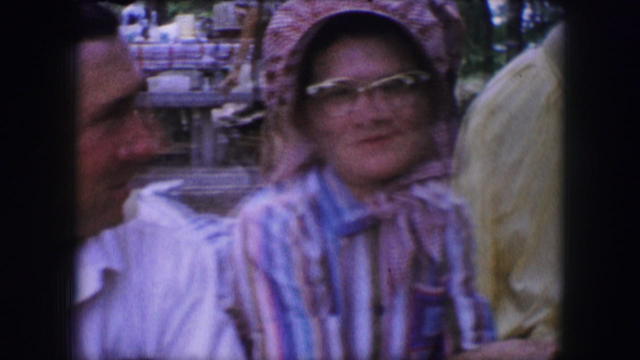 Adults seated at a picnic table, including a woman in glasses and a headscarf.
