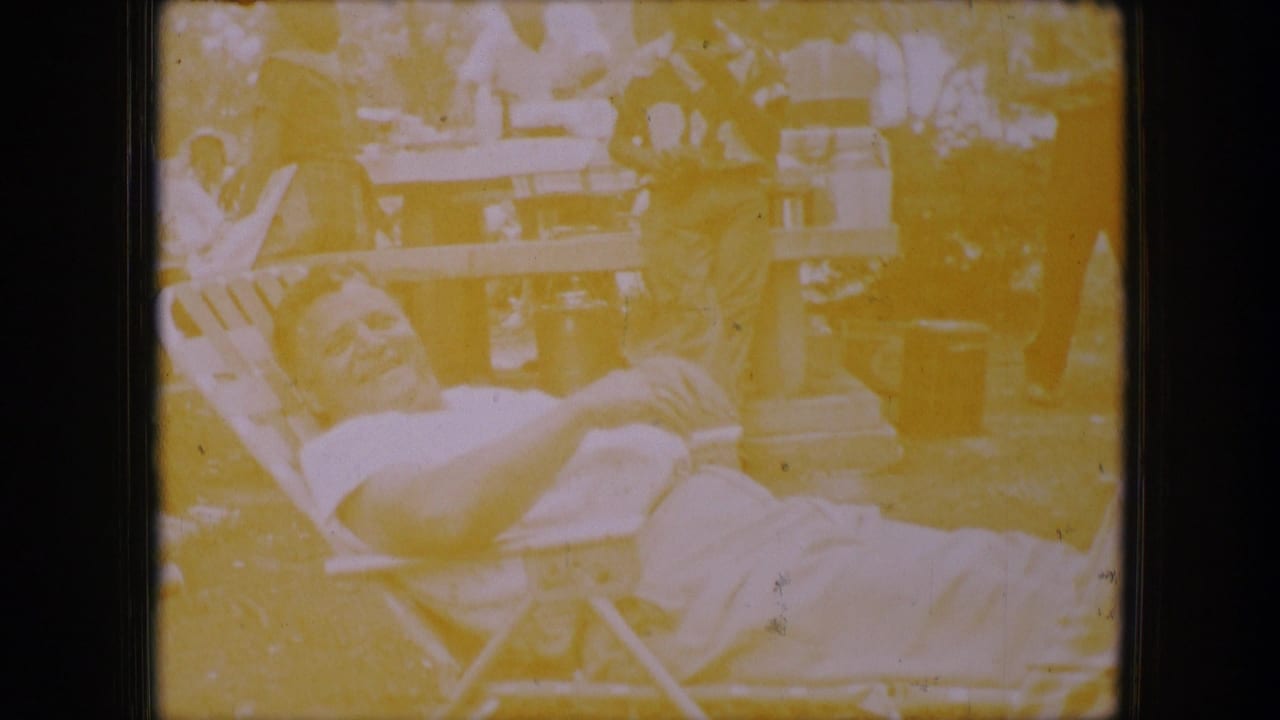 Overexposed frame of a man reclining in a folding chair near picnic tables.