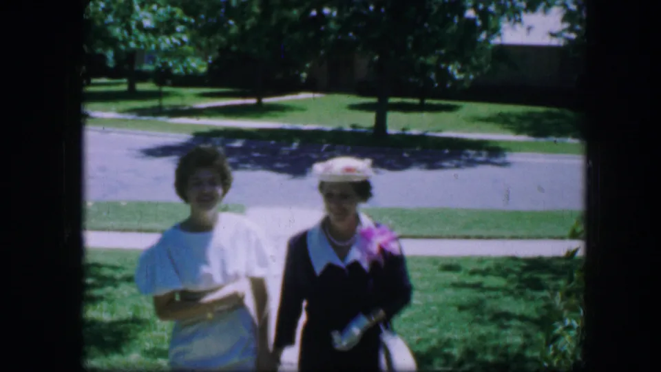 Close view of two adult women in formal dress approaching the camera in 1964 Fort Worth home-movie footage.
