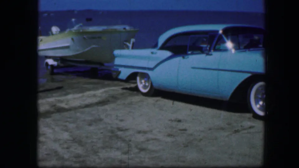 A turquoise vintage car and trailered boat appear beside a lake in 1964 Fort Worth home-movie footage.