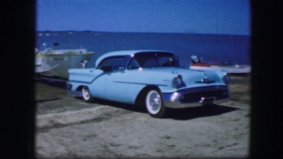 A turquoise vintage car, trailered boat, and lake shoreline are shown in 1964 Fort Worth home-movie footage.
