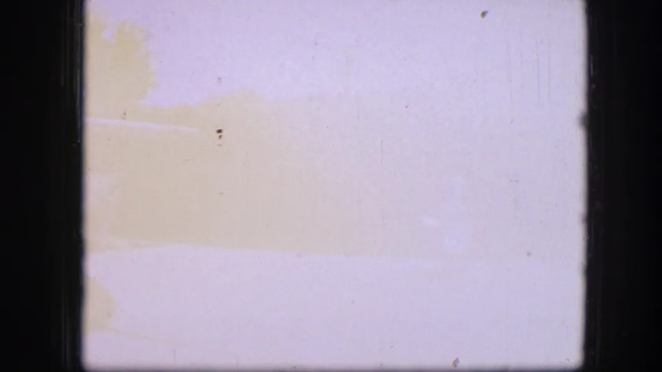 Mostly overexposed 8mm frame with faint warm color bands and minimal visible subject detail.