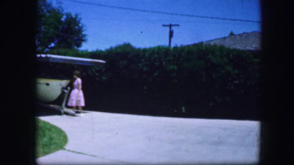 At the end of the 1964 Fort Worth clip, the woman appears to reach down near the covered structure in the backyard driveway.