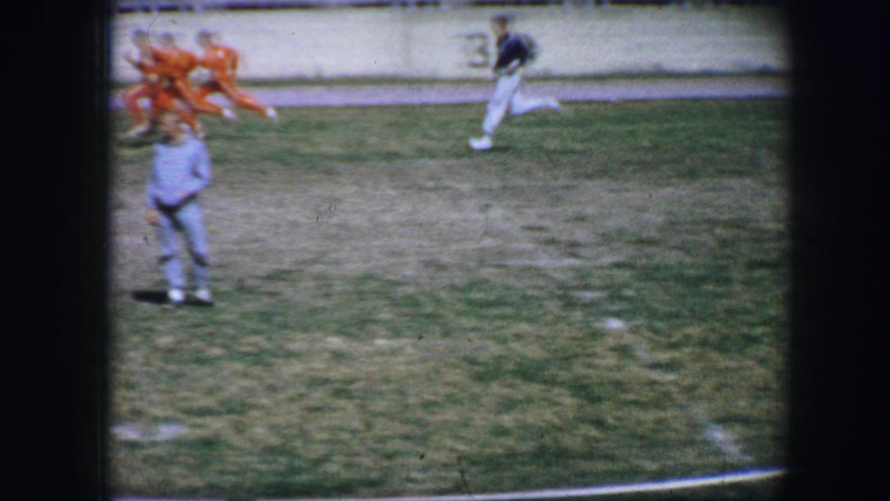 Runners on a grassy track field with an official standing in the foreground.
