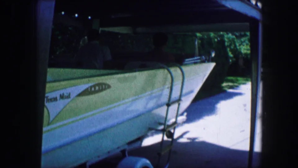 Closer 1965 Lewisville, Texas frame of a light-colored small aircraft on a trailer, with partial lettering visible but not confidently readable.