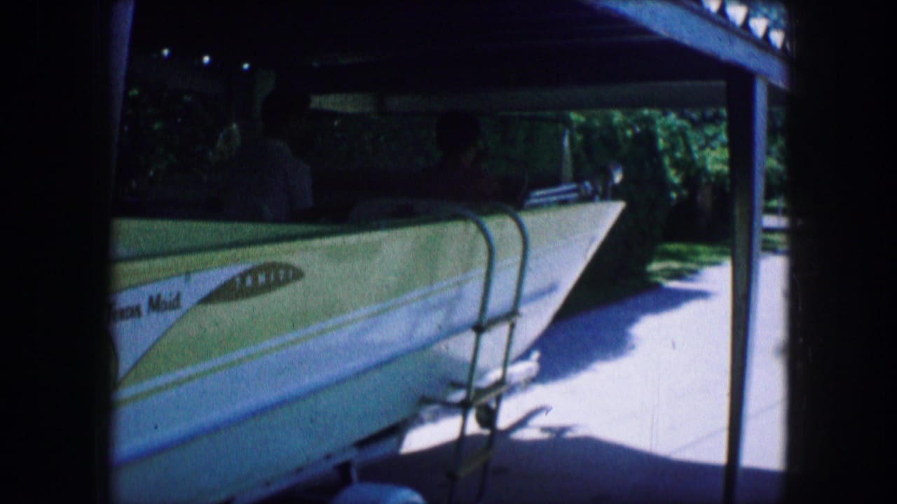 Yellow-and-white speedboat on a trailer beside a driveway under a carport.
