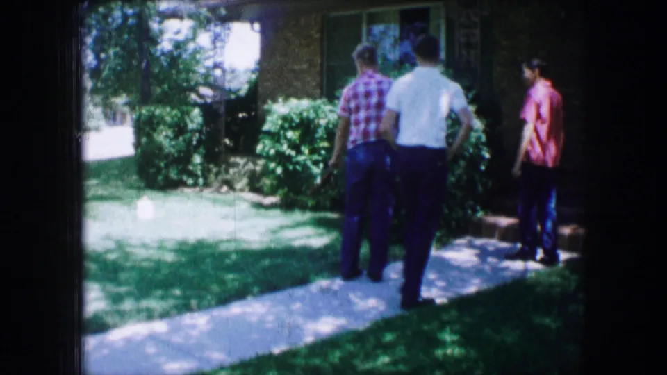A 1965 Lewisville, Texas yard scene with three figures gathered near the front path, shrubs, and house windows.