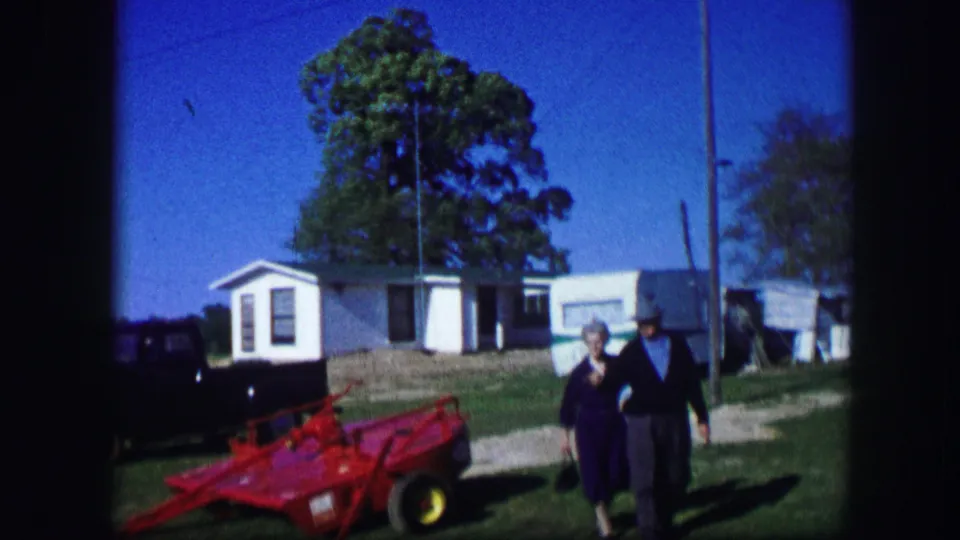 Near the end of the 1967 Kirksville clip, the woman and man approach the camera beside the red toy car and mobile home setting.