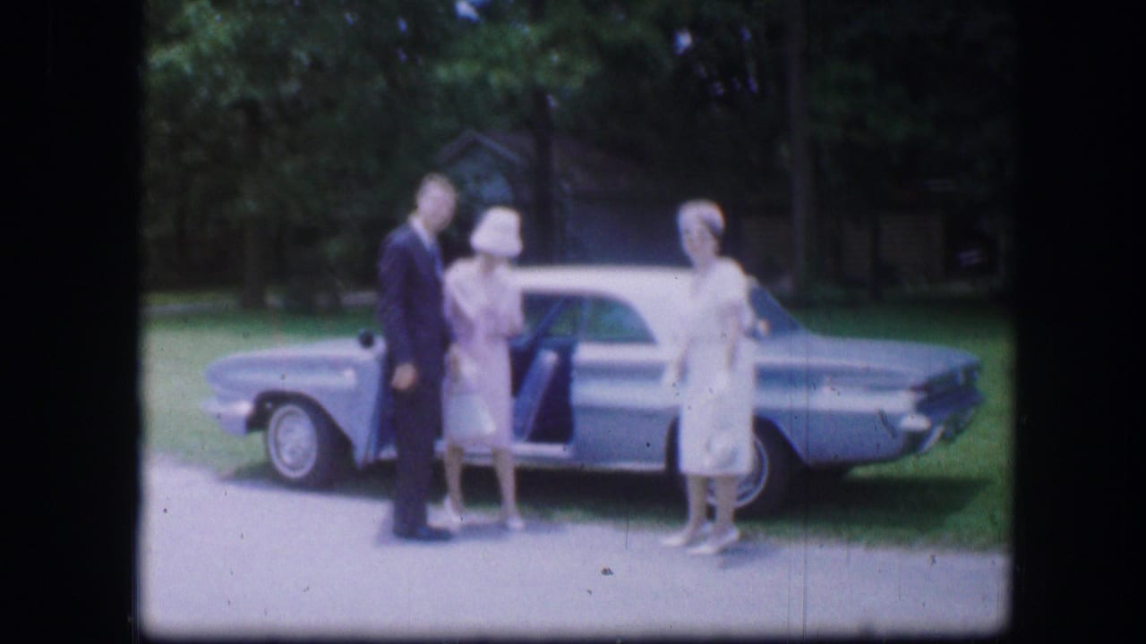 In Kirksville, Missouri, three adults pose outdoors beside a light blue car in 1967 home-movie footage.