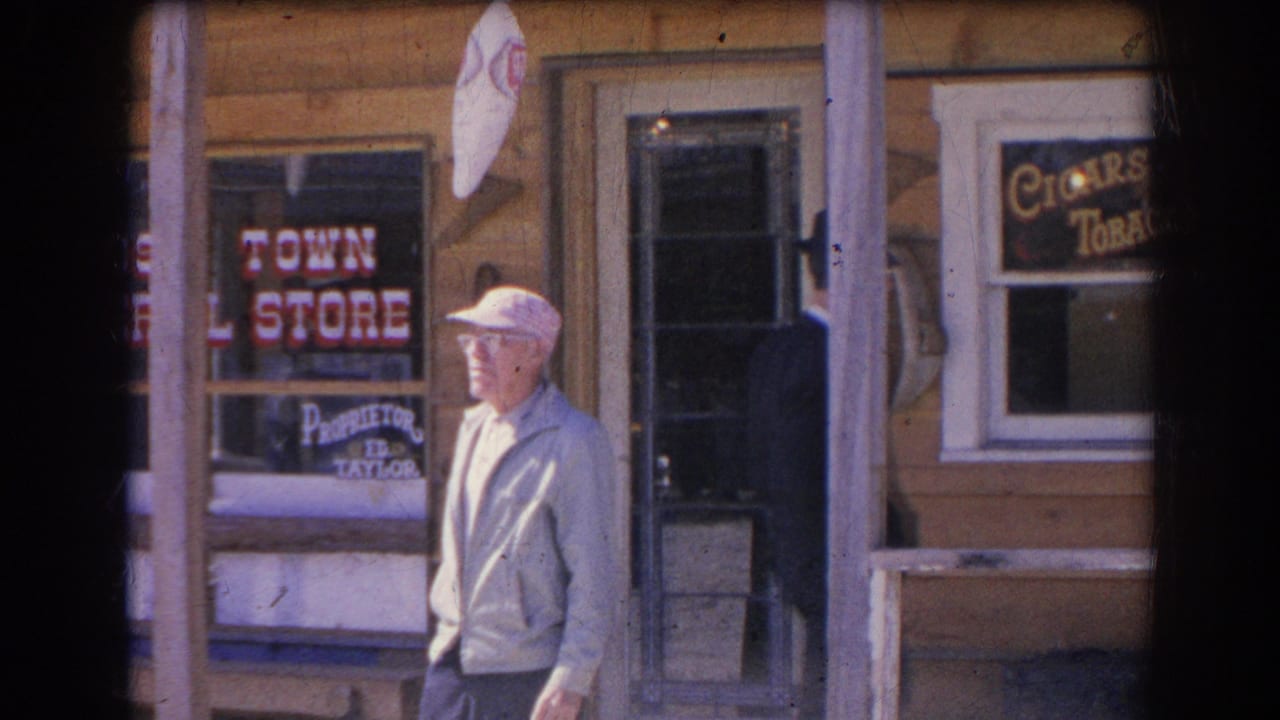 Older man in a white cap stands outside a wooden storefront with window lettering.