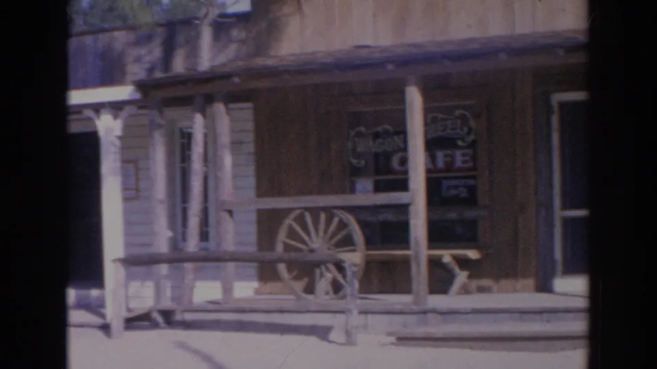 1969 Sarasota frame showing the Wagon Wheel Cafe porch, windows, wooden rails, and wagon wheel decor.