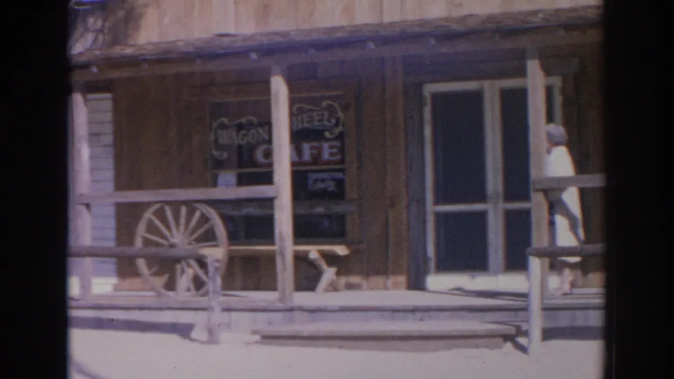 1969 Sarasota frame of the Wagon Wheel Cafe exterior with porch posts, window sign, rail fence, and screen door.