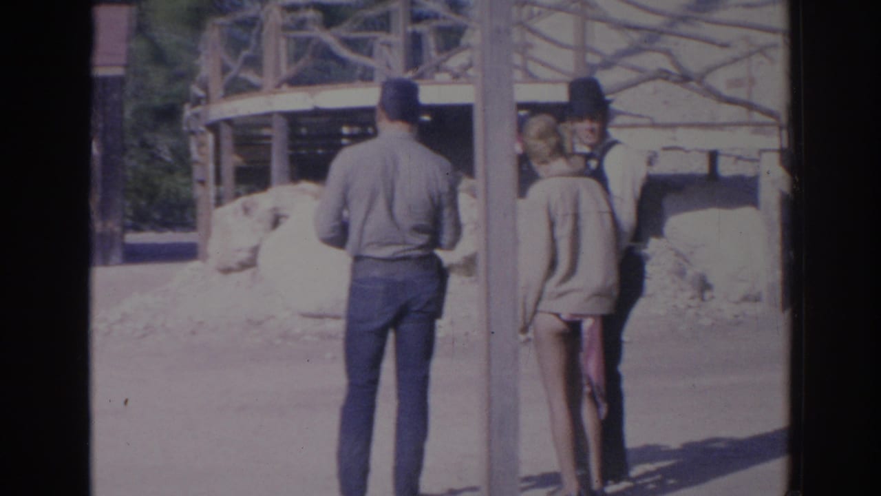 1969 Sarasota-area 8mm frame showing visitors or performers near wooden posts and rustic Western-style structures.