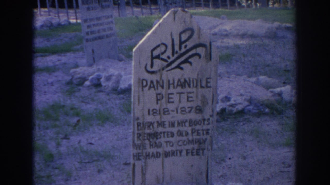 Close 1969 Sarasota frame of the Pan Handle Pete marker, with dark painted lettering, rough ground, stones, and fencing in the background.