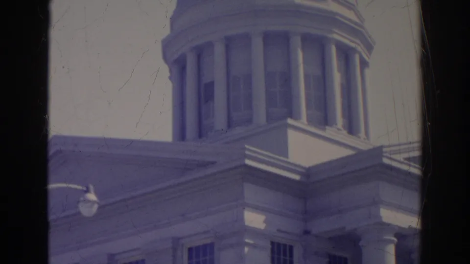 The 8mm frame shows a closer angled view of the domed building, including columns, windows, trim, and a visible exterior lamp.