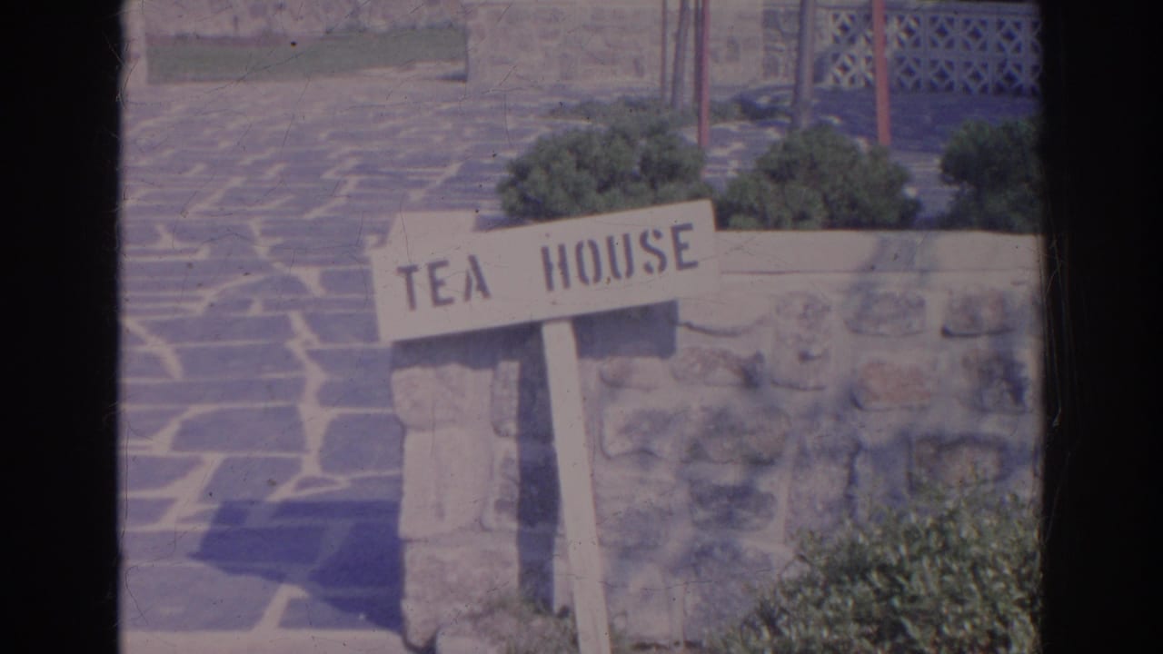 Wooden Tea House sign beside a stone wall and paved garden path.