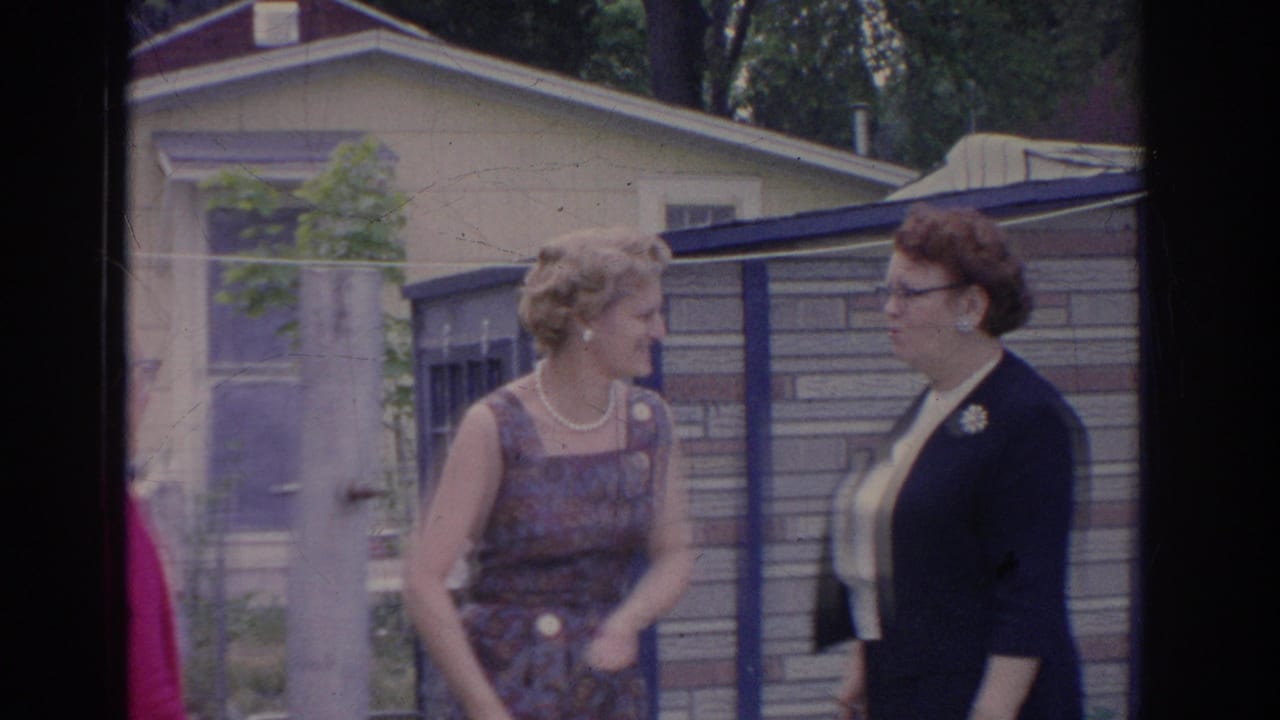 In 1969 Sarasota home-movie footage, two women converse beside a fence and nearby house in a suburban yard.