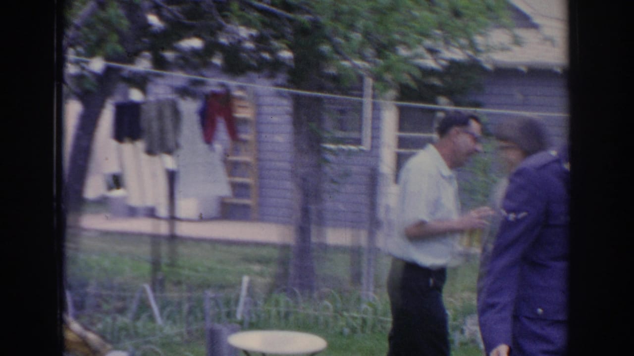 Two adult men appear in a suburban Sarasota yard near a clothesline, fence, and house exteriors in 1969 footage.