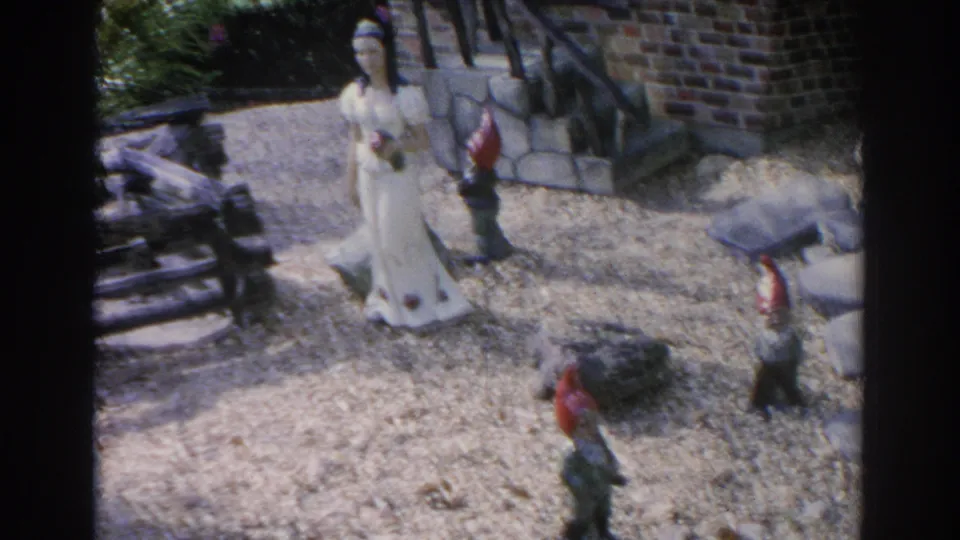 1969 Sarasota frame showing character statues arranged in a landscaped storybook garden setting.