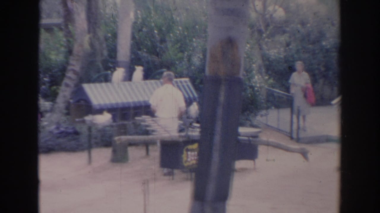 Garden walkway with benches, railings, planting beds, and distant visitor-like figures.